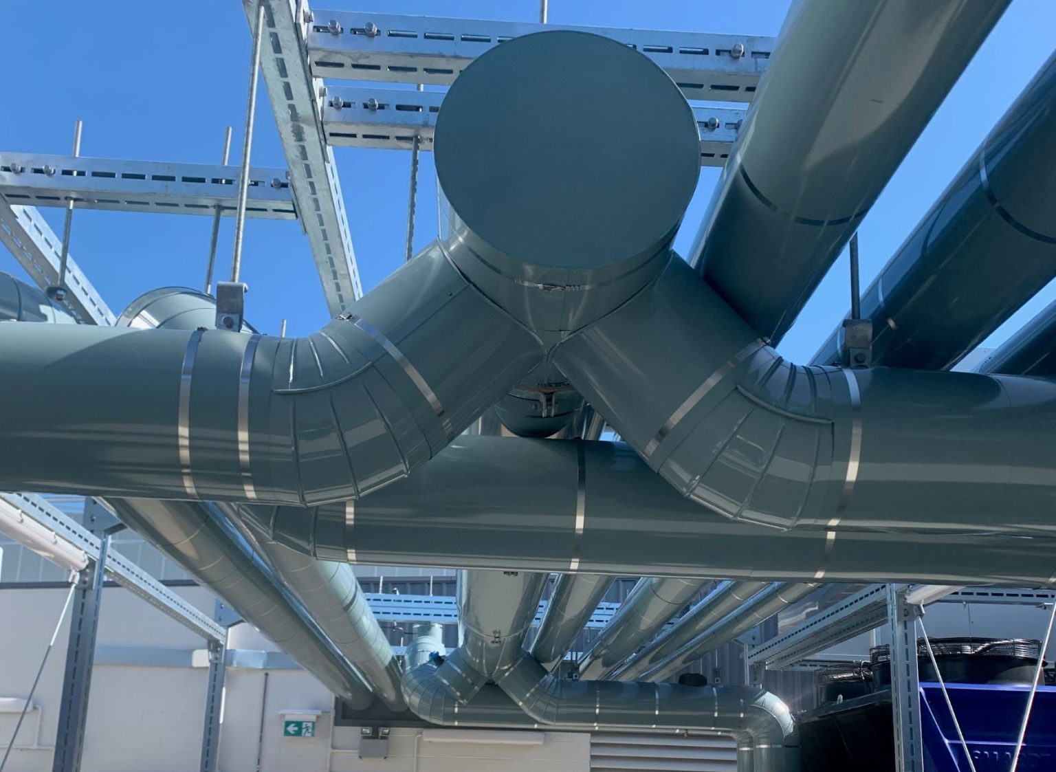 Aluminium clad ductwork and pipework on a rooftop against the sky